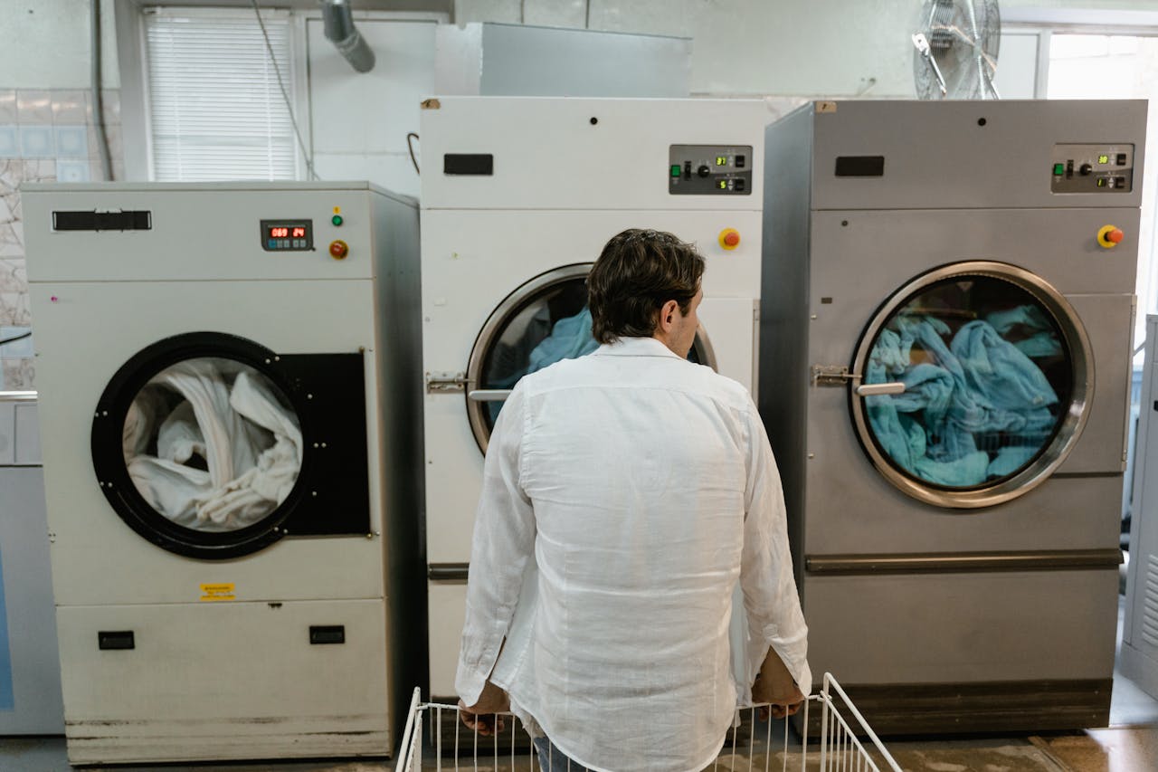 services-01 A man uses commercial washing machines at an indoor laundromat.