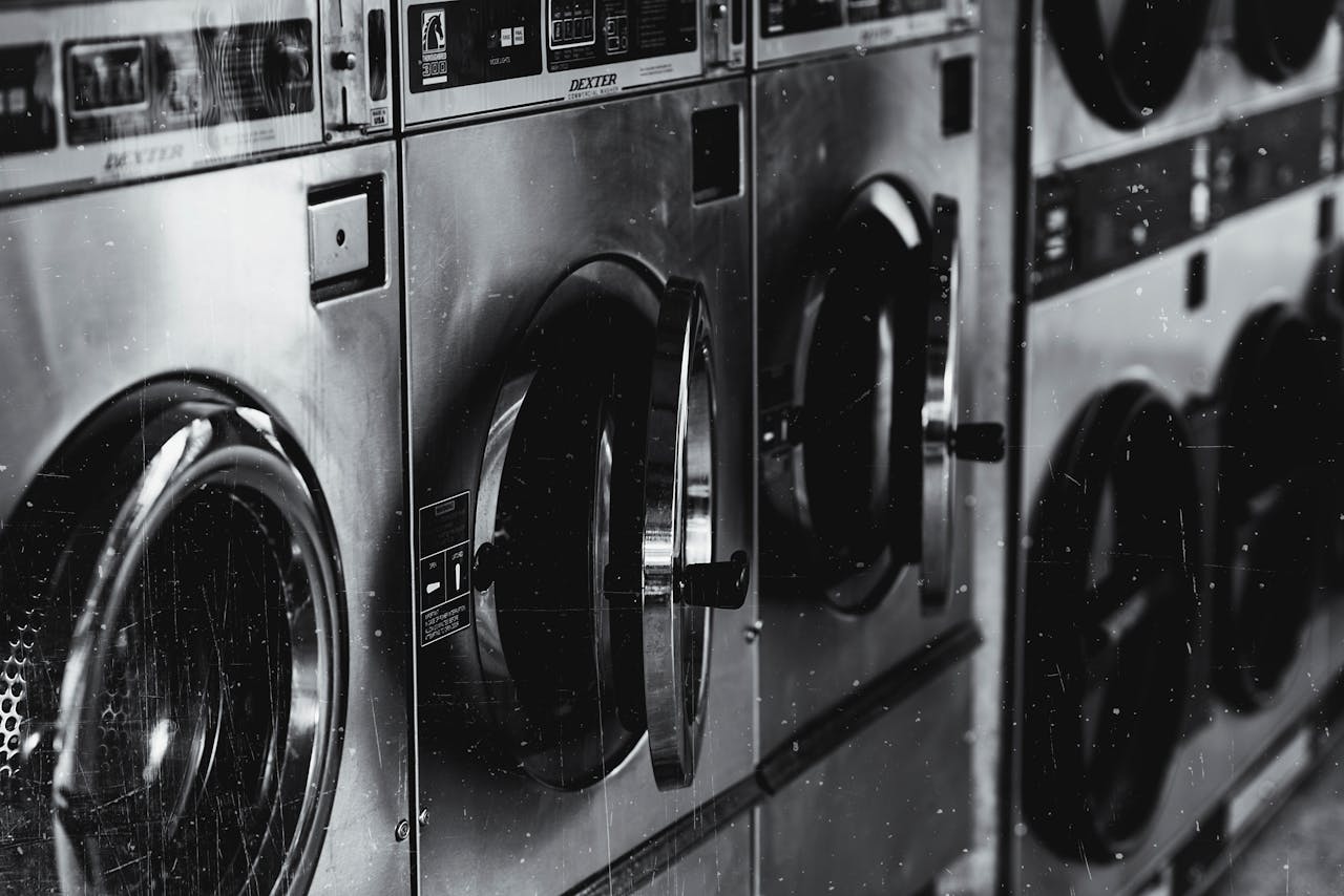 services-03 Black and white image of industrial washing machines in a retro style laundry facility.