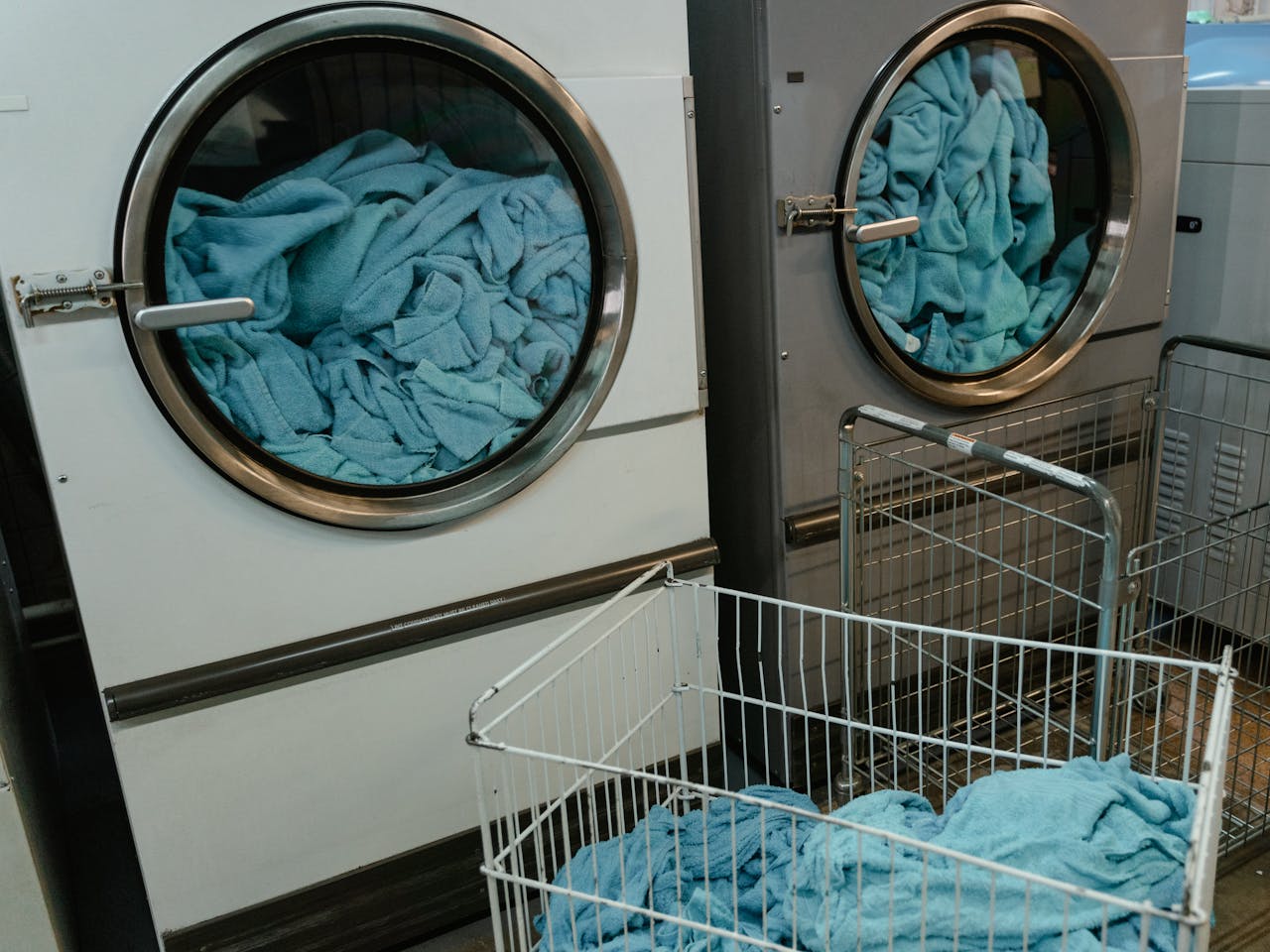 hero-img-01 Industrial washing machines with blue towels in a laundry facility.