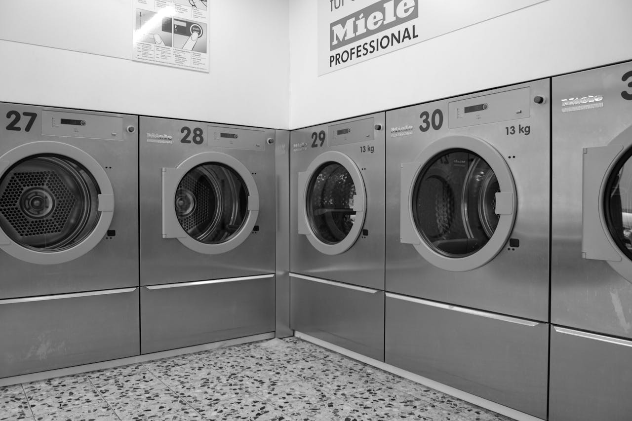 about-01 A sleek row of industrial washing machines in a modern laundromat, conveying efficiency and cleanliness.